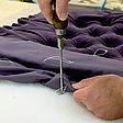 Näharbeiten an Kopfteil von Treca Interiors in violett mit Knopfheftung