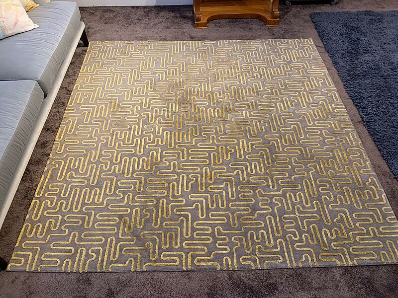 Grauer Teppich mit gelbem Linienmuster 
